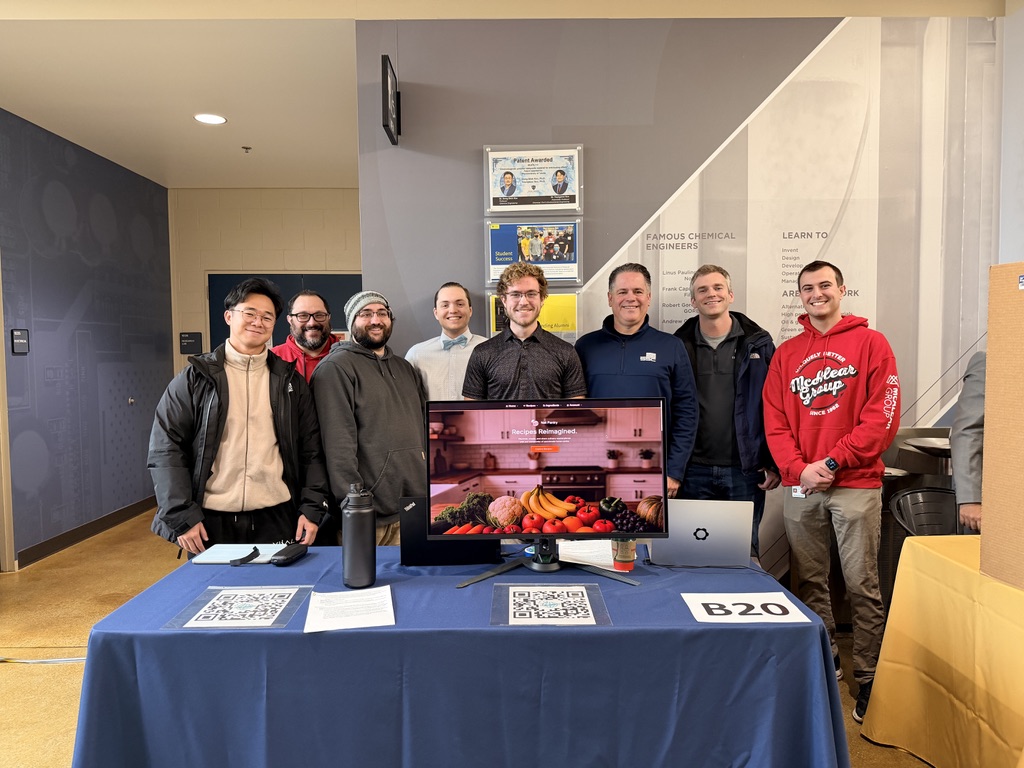 Group of coworkers and boss standing behind project booth for Net Pantry at the University of Toledo&rsquo;s senior design expo