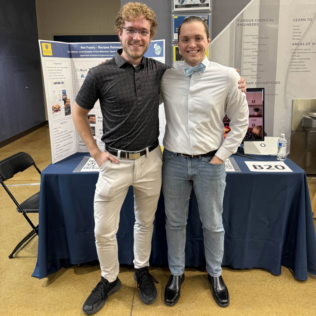 Two students smiling at their project booth for Net Pantry at the University of Toledo&rsquo;s senior design expo